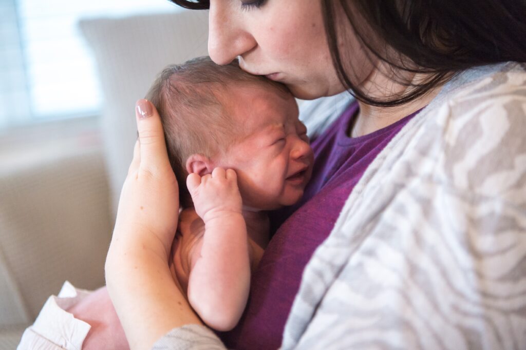 Mother kissing new born baby on forehead